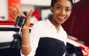 Woman buying the car. Lady in a car salon. Elegant black girl